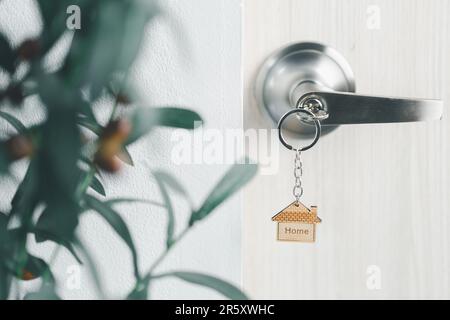 Nahaufnahme Schlüssel an der Tür mit Morgenlicht, persönliches Leihkonzept. Hausmodell und Schlüssel in Haustür. Immobilienmakler bieten Haus an, Immobilienversicherer Stockfoto