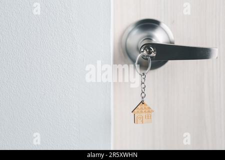Nahaufnahme Schlüssel an der Tür mit Morgenlicht, persönliches Leihkonzept. Hausmodell und Schlüssel in Haustür. Immobilienmakler bieten Haus an, Immobilienversicherer Stockfoto