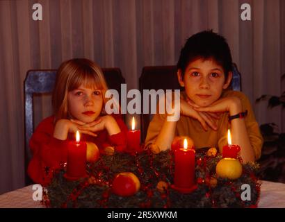 2 zwei Kinder sitzen im Adventskranz, 4 vier brennende Kerzen, yule-Flut, Advent, 2 zwei Kinder sitzen im Adventskranz, 4 vier brennende Kerzen Stockfoto