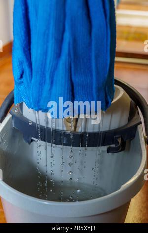 Nahaufnahme eines blauen Mopps, der Tropfen Wasser in seinen Eimer tropft Stockfoto