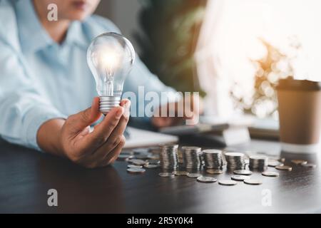 Geschäftsfrau, die eine Glühbirne mit einem Kostenrechner hält. Idee von Energie- und Buchhaltungsfinanzen zu Hause und in der Familie zu sparen, Welt zu retten und Energie zu fördern Stockfoto