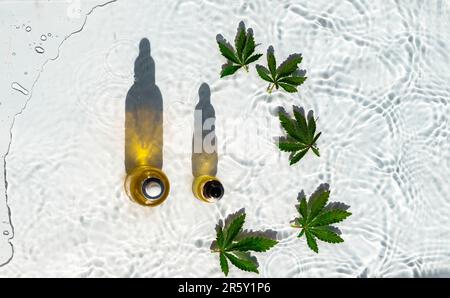 CBD-Ölflaschen, Weißwasser-Hintergrund mit Tropfen, Wellen und Blättern aus Hanf, Marihuana Stockfoto