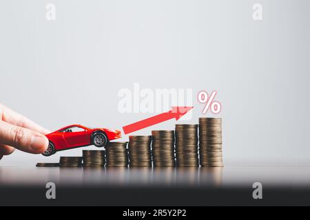 Stapel Münzen und rotes Auto mit Prozentsymbol für die Erhöhung der Zinssätze. Finanzzinssätze und Hypothekenzinsen. Symbol Prozentsymbol A Stockfoto