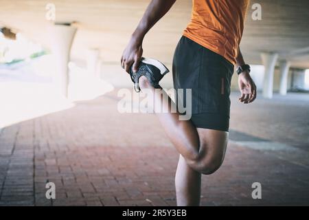 Die Knie der Läufer sind echt, bleib auf der sicheren Seite. Ein Mann, der sich während eines Workouts vor urbanem Hintergrund dehnt. Stockfoto