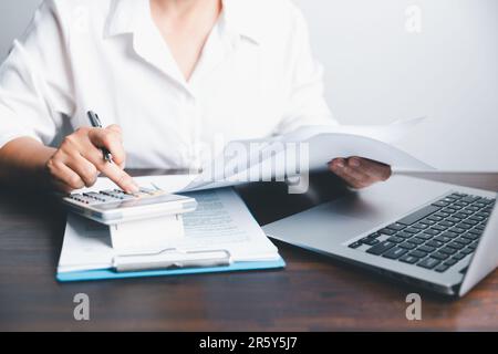 Nahaufnahme Frau mit Taschenrechner zählt zu Hause Notizen, Hand schreibt in einem Notizbuch. Asiatische Frau überprüft Rechnungen, Steuern, Kontostand A Stockfoto