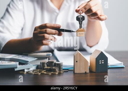 Der Hausmakler hält die Schlüssel und das Modellhaus wird den Kunden ausgehändigt. Hausmodell mit Immobilienmakler mit Kunde für s. Stockfoto