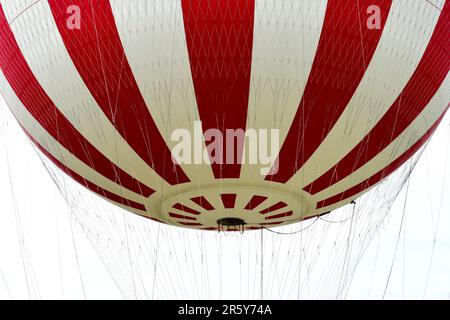 Schwebende Details im rot-weißen gasgefüllten Abenteuerballon. Hängeseile hängen. Kabel. Nahaufnahme mit niedrigem Winkel. Besichtigungstour in Budapest. Stockfoto