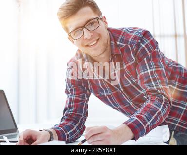 Rückansicht eines Geschäftsmanns, der vor dem Laptop-Bildschirm sitzt. Ein Mann, der in einem Büro auf einem modernen Laptop tippt. Junger Student, der auf einem Computer tippt Stockfoto