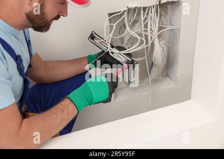 Elektriker mit Schraubendreher-Befestigung Patchpanel in Innenräumen, Nahaufnahme Stockfoto