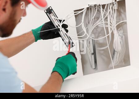 Elektriker mit schraubendrehbarem Patchpanel im Innenbereich Stockfoto