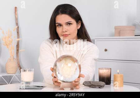 Wahrsager mit Kristallkugel, um die Zukunft am Tisch im Raum vorherzusagen Stockfoto