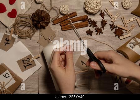 Eine nicht erkennbare junge Frau malt Zahlen auf Kerzen. Frau macht hausgemachte Adventskalender mit eigenen Händen gemacht Schritt für Schritt selbstgemachtes Kunsthandwerk Machen Sie es selbst. Vorbereitung auf das weihnachtskonzept. Saisonale Aktivitäten für Kinder, Familienurlaub im Winter. Umweltfreundlich Geschenke. Öffnen Sie das Paket jeden Tag Stockfoto