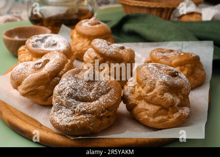 Köstliche Profiteroles mit Puderzucker auf grünem Hintergrund Stockfoto