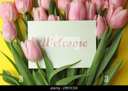 Begrüßungskarte mit wunderschönen rosa Tulpen auf gelbem Hintergrund, Draufsicht Stockfoto