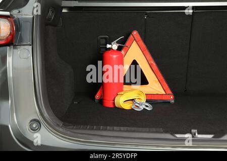 Roter Feuerlöscher, Abschleppgurt und klappbares Warndreieck im Kofferraum. Fahrzeugsicherheit Stockfoto