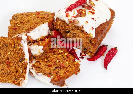 Wütender Karottenkuchen, Karottenkuchen mit Chiliflocken. Dekadente süße und würzige Leckerei. In Scheiben mit Chili auf Weiß Stockfoto