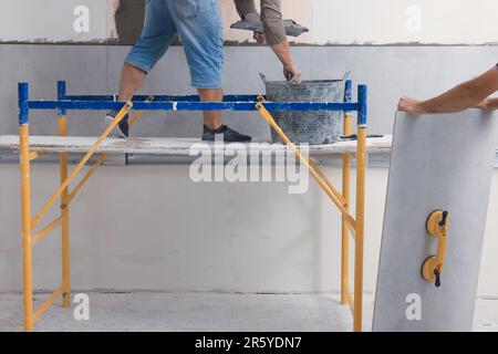 Arbeiter, der Keramikfliesen an der Wand in Innenräumen installiert, schließt Stockfoto