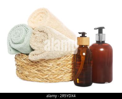 Weiche Handtücher in Korb und Flaschen mit Kosmetikprodukten auf weißem Hintergrund Stockfoto