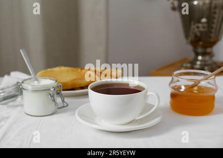 Klassischer Samovar, eine Tasse heißes Getränk und Snacks werden auf dem Tisch serviert. Traditionelle russische Teezeremonie Stockfoto