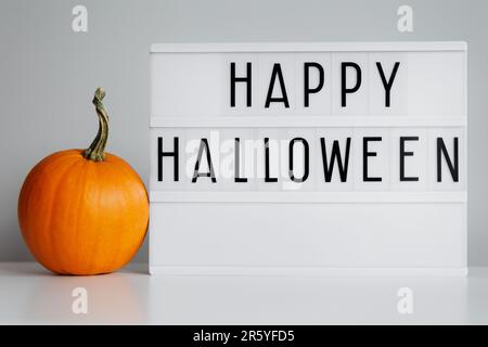 Lightbox mit Happy halloween Text und kleinem orangefarbenen Kürbis Stockfoto