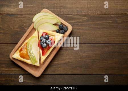 Frisches, leckeres Blätterteig mit Marmelade, Blaubeeren und Birne auf einem Holztisch, Draufsicht. Platz für Text Stockfoto