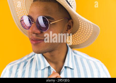 Nahaufnahme eines afroamerikanischen Mannes mit Strohhut und Sonnenbrille vor hellem Hintergrund. Hochwertiges Foto Stockfoto