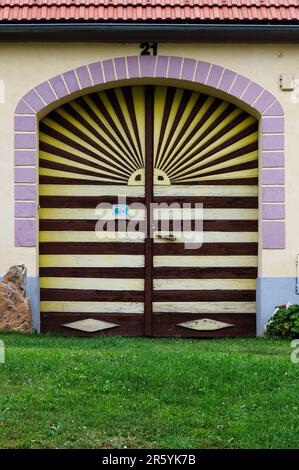 Hüten Sie sich vor dem Hundeschild am verschlossenen, breiten Eingang in Holašovice, Südböhmen, Tschechien oder Tschechien. Holašovice ist ein gut erhaltenes Beispiel für ein traditionelles mitteleuropäisches Dorf mit vielen Häusern, die in den 1800er v. Chr. in einem Stil wiederaufgebaut wurden, der als südböhmisches Volksharock, ländliches Barock oder Rustisches Barock bekannt ist. 1997 wurde das Dorf in die UNESCO-Liste des Weltkulturerbes aufgenommen. Stockfoto