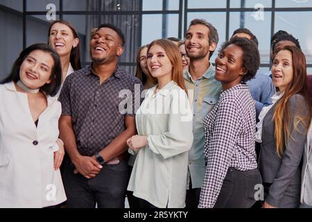 Lächelnde junge, ethnische Arbeitergruppen stellen sich zusammen als Humanressourcen dar Stockfoto