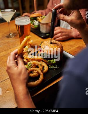 Nahaufnahme von jungen multiethnischen Freunden in legerer Kleidung, die Fast Food im Restaurant genießen Stockfoto