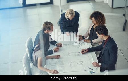 Auf der Basis von Executive-Design. Ein Team von Unternehmensarchitekten, das in einem modernen Büro an einem Plan arbeitet. Stockfoto