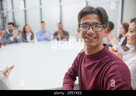 Junger, gutaussehender Geschäftsmann mit Brille, der vor der Kamera posiert Stockfoto