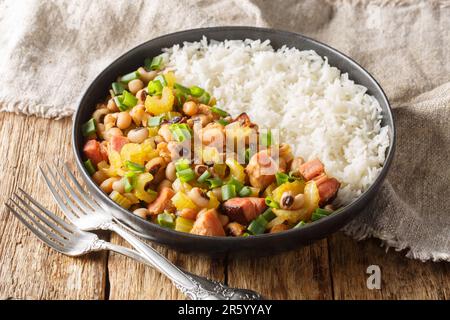 Hoppen Sie Johannes mit schwarzen Augen, Schinken, Würstchen, Gemüse und Zwiebeln mit Reisnaht auf dem Holztisch. Horizontal Stockfoto