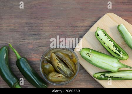 Frische und eingelegte grüne Jalapeno-Paprika auf Holztisch, flach liegend. Platz für Text Stockfoto