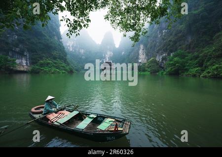 Boot rudert am Thung Chuoi Tempeltor zwischen üppigen grünen Karstbergen, Trang an, Ninh Binh, Vietnam Stockfoto