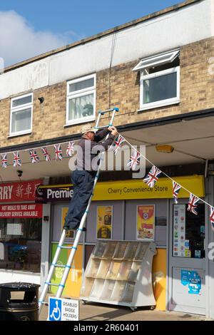 Ein Mann hängt die Gewerkschaftsflagge im Einkaufszentrum auf, um die Karl-III-Krönung zu feiern, die Parade Cherry Willingham Lincolnshire, England, Großbritannien Stockfoto