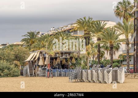 Terrasse einer Bar am Poniente Strand mit Dach, Lichtern, Palmen, Stühlen und Tischen in der Stadt Salou, Costa Daurada, Tarragona, Katalonien. Stockfoto