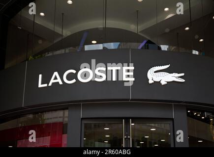 Ho-Chi-Minh-Stadt, Vietnam - 4. Juni 2023: Handelsschild für Modegeschäfte mit schwarzweißem Lacoste-Logo. Berühmtes Logo der Luxusmarke oben Stockfoto