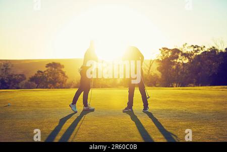 Wir haben gerade Golf gespielt, sagen wir, es war ein Hit. Zwei Golfspieler schütteln sich die Hand auf dem Golfplatz. Stockfoto