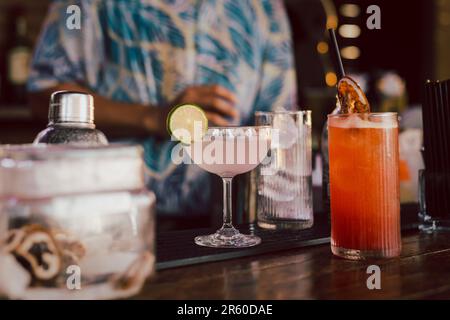 Batender macht ein rosafarbenes, kosmopolitisches Cocktailgetränk mit einem Stück Limette. Stockfoto