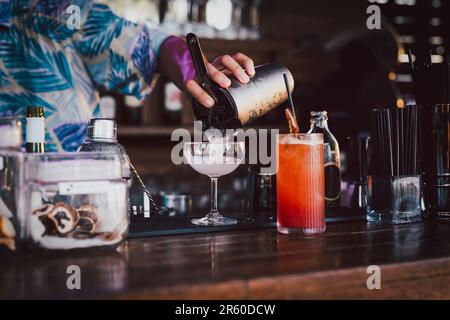 Der Barkeeper macht Cocktails, die in ein martini-Glas gegossen werden. Stockfoto