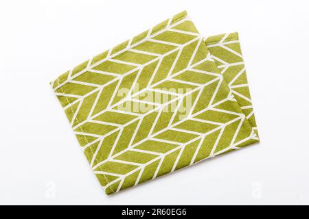 Draufsicht mit grüner Serviette auf Tischhintergrund isoliert. Gefaltetes Tuch für Modell mit Kopierbereich, flach liegend. Minimalistischer Style. Stockfoto