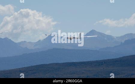 Ein Gleiter, der vor dem Hintergrund von Bergen am Himmel aufsteigt Stockfoto