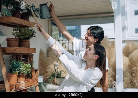 Liebhaber verbringen ihre Zeit damit, auf den stilvollen Balkonen auf dem Dach kleine Gärten, Pflanzen und frische Blumen zu bewässern. Entspannen Sie sich in ordentlichem Raum. Mit der Natur zurechtkommen Stockfoto