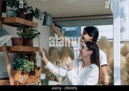 Liebhaber verbringen ihre Zeit damit, auf den stilvollen Balkonen auf dem Dach kleine Gärten, Pflanzen und frische Blumen zu bewässern. Entspannen Sie sich in ordentlichem Raum. Mit der Natur zurechtkommen Stockfoto