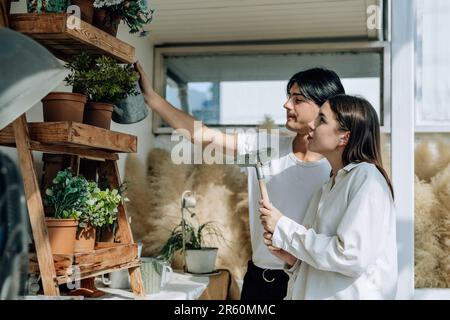 Liebhaber verbringen ihre Zeit damit, auf den stilvollen Balkonen auf dem Dach kleine Gärten, Pflanzen und frische Blumen zu bewässern. Entspannen Sie sich in ordentlichem Raum. Mit der Natur zurechtkommen Stockfoto