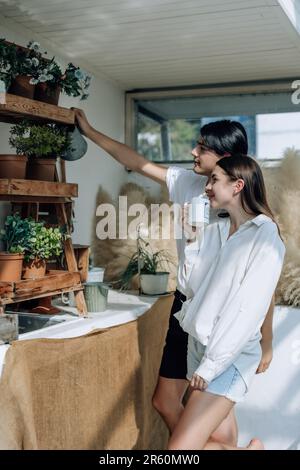 Liebhaber verbringen ihre Zeit damit, auf den stilvollen Balkonen auf dem Dach kleine Gärten, Pflanzen und frische Blumen zu bewässern. Entspannen Sie sich in ordentlichem Raum. Mit der Natur zurechtkommen Stockfoto