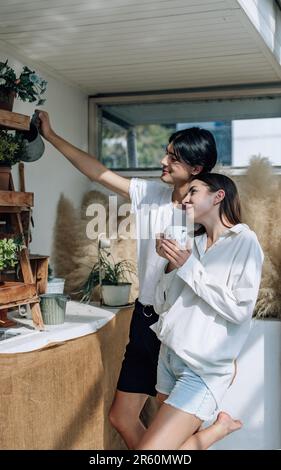 Liebhaber verbringen ihre Zeit damit, auf den stilvollen Balkonen auf dem Dach kleine Gärten, Pflanzen und frische Blumen zu bewässern. Entspannen Sie sich in ordentlichem Raum. Mit der Natur zurechtkommen Stockfoto