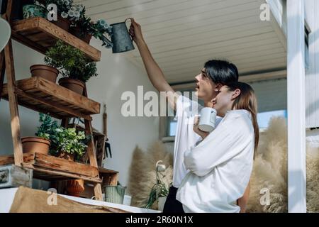 Liebhaber verbringen ihre Zeit damit, auf den stilvollen Balkonen auf dem Dach kleine Gärten, Pflanzen und frische Blumen zu bewässern. Entspannen Sie sich in ordentlichem Raum. Mit der Natur zurechtkommen Stockfoto