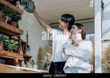 Liebhaber verbringen ihre Zeit damit, auf den stilvollen Balkonen auf dem Dach kleine Gärten, Pflanzen und frische Blumen zu bewässern. Entspannen Sie sich in ordentlichem Raum. Mit der Natur zurechtkommen Stockfoto