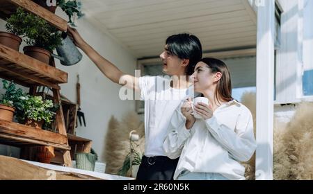 Liebhaber verbringen ihre Zeit damit, auf den stilvollen Balkonen auf dem Dach kleine Gärten, Pflanzen und frische Blumen zu bewässern. Entspannen Sie sich in ordentlichem Raum. Mit der Natur zurechtkommen Stockfoto